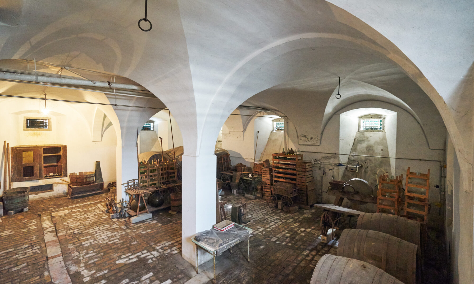 Kellergewölbe mit alten Weinfässern und Mostflaschen
