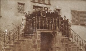 Schwarz-Weiss-Fotografie der Bewohnerinnen und Bewohner des Oberhauses, die auf der nördlichen Freitreppe vor dem Haus posieren