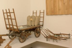 Modell eines Heuwagens und zwei Pflugmodelle aus Holz mit Eisenbeschlägen