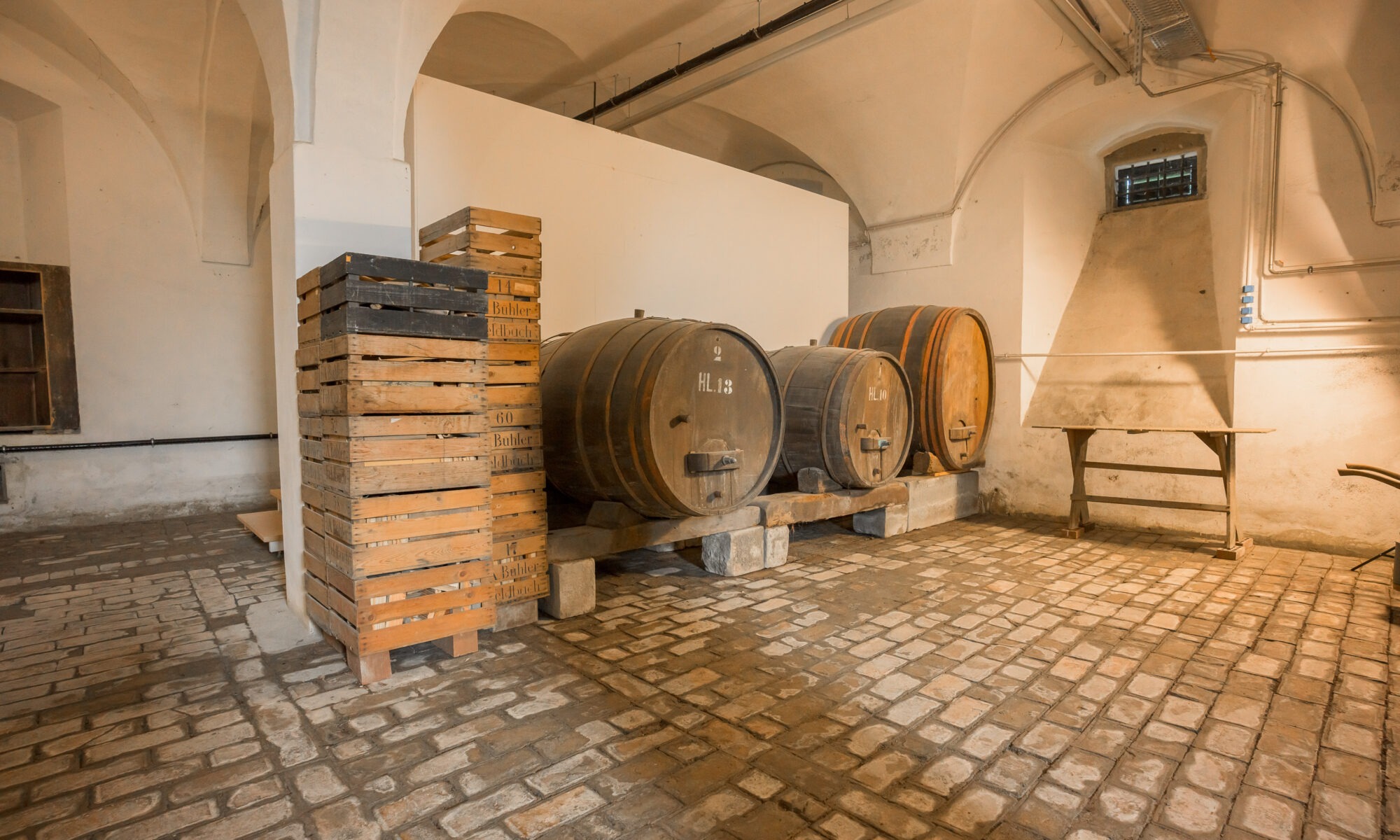 drei alte Holzfässer und ein Stapel Holzharassen im Keller des Oberhauses