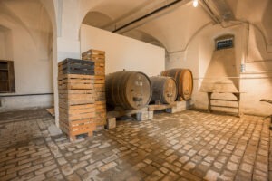 drei alte Holzfässer und ein Stapel Holzharassen im Keller des Oberhauses